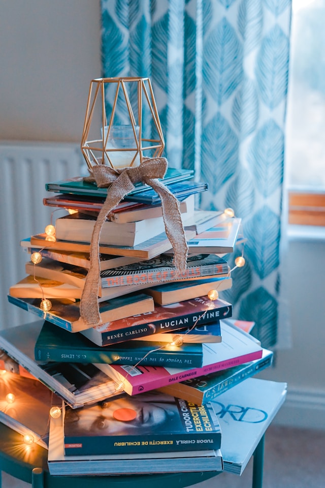 stack of books with fairy lights