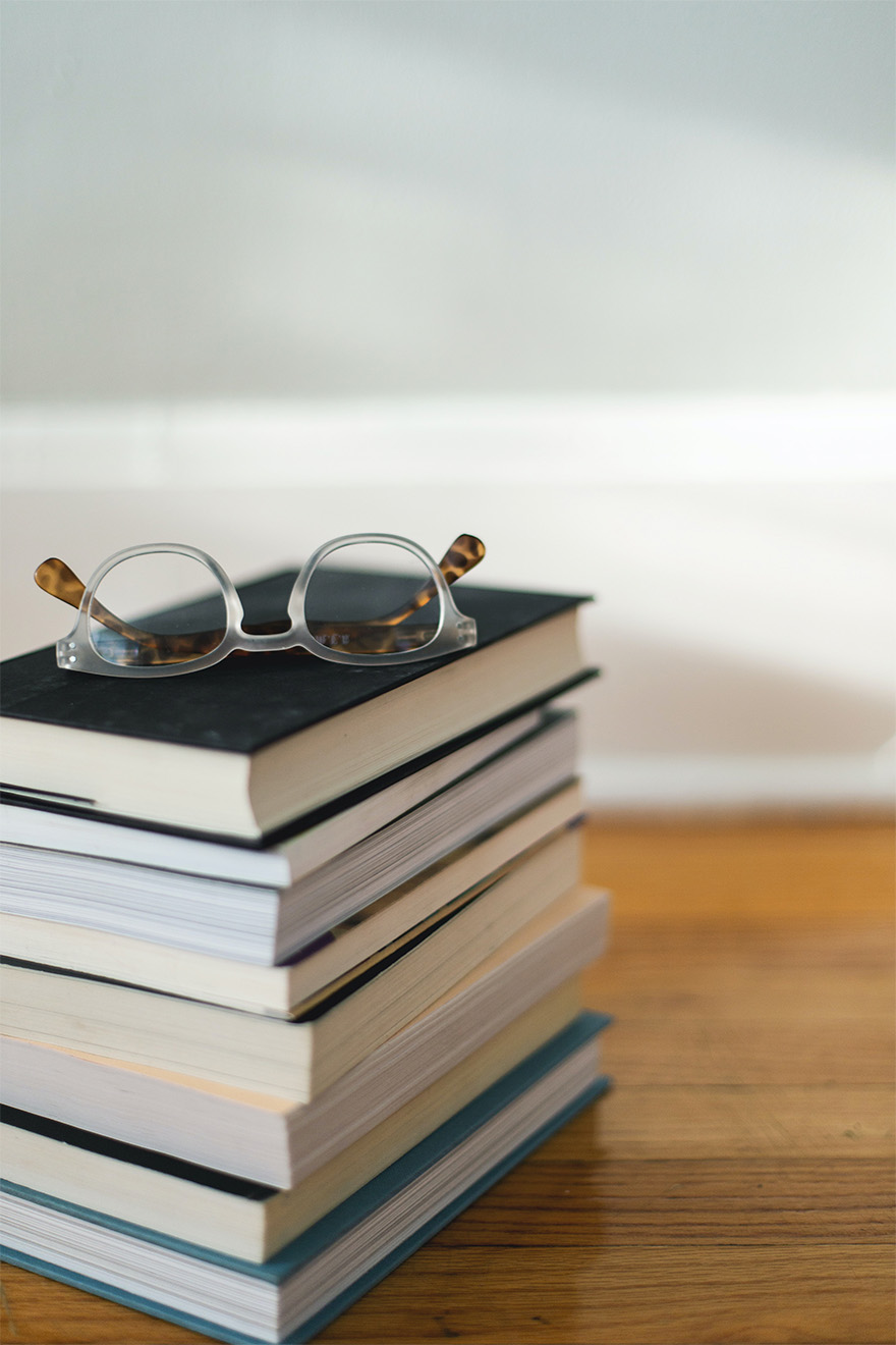 stack of books with reading glasses on top